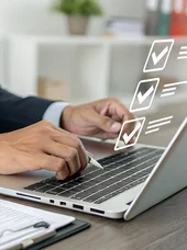 Zertifikatslehrgang "Fachkraft Fördermittelmanagement in der öffentlichen Verwaltung" Eine Person sitzt an einem Laptop. Vor dem Bildschirm des Laptops ist ein hologrammartiges Display zu erkennen.