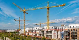 Öffentliches Baurecht Wachsendes Stadtquartier mit Wohnhäusern im Rohbau, Baukränen und begrünten Erschließungsstraßen