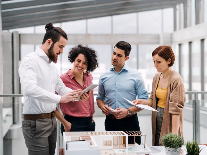 architekten-c-halfpoint-adobestock Architektenteam bespricht sich zu einem Gebäudemodell.